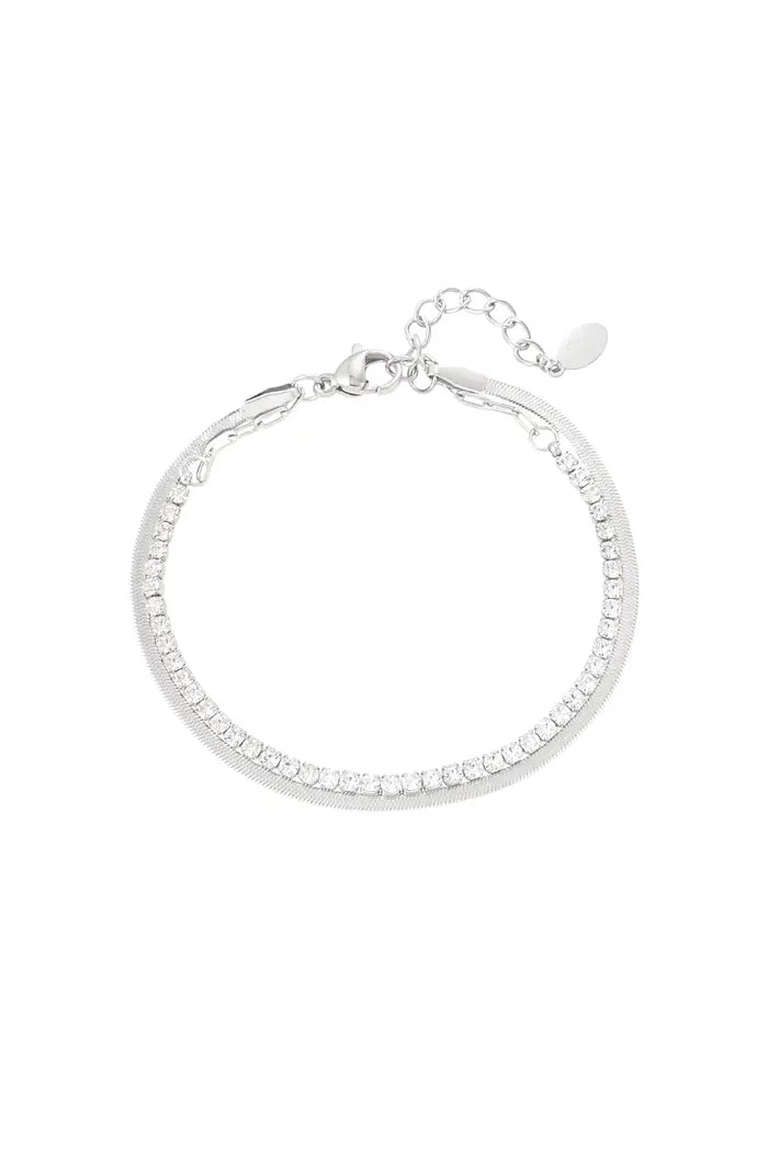 Zilveren dubbele armband met sprankelende diamantjes, subtiel gestyled op een neutrale achtergrond.