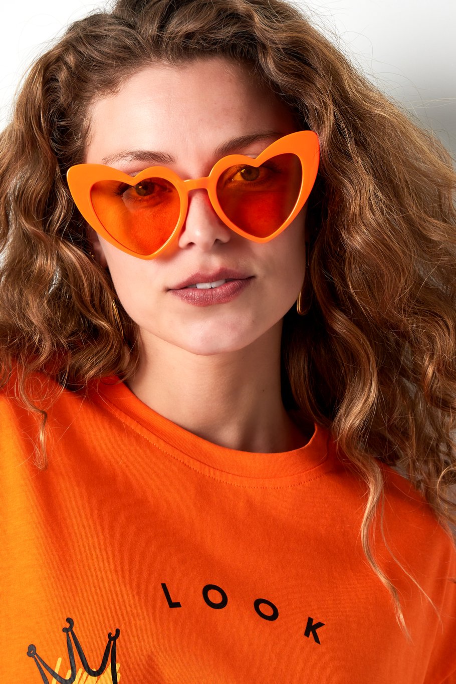 Trendy oranje zonnebril met schattig hartmotief, perfect voor een speelse en liefdevolle look.