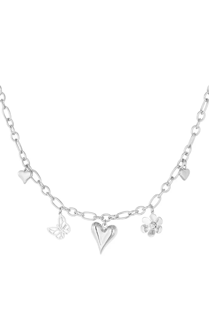 Zilveren bedelketting met delicate hart- en vlinderbedels, elegant gepresenteerd op een witte achtergrond.